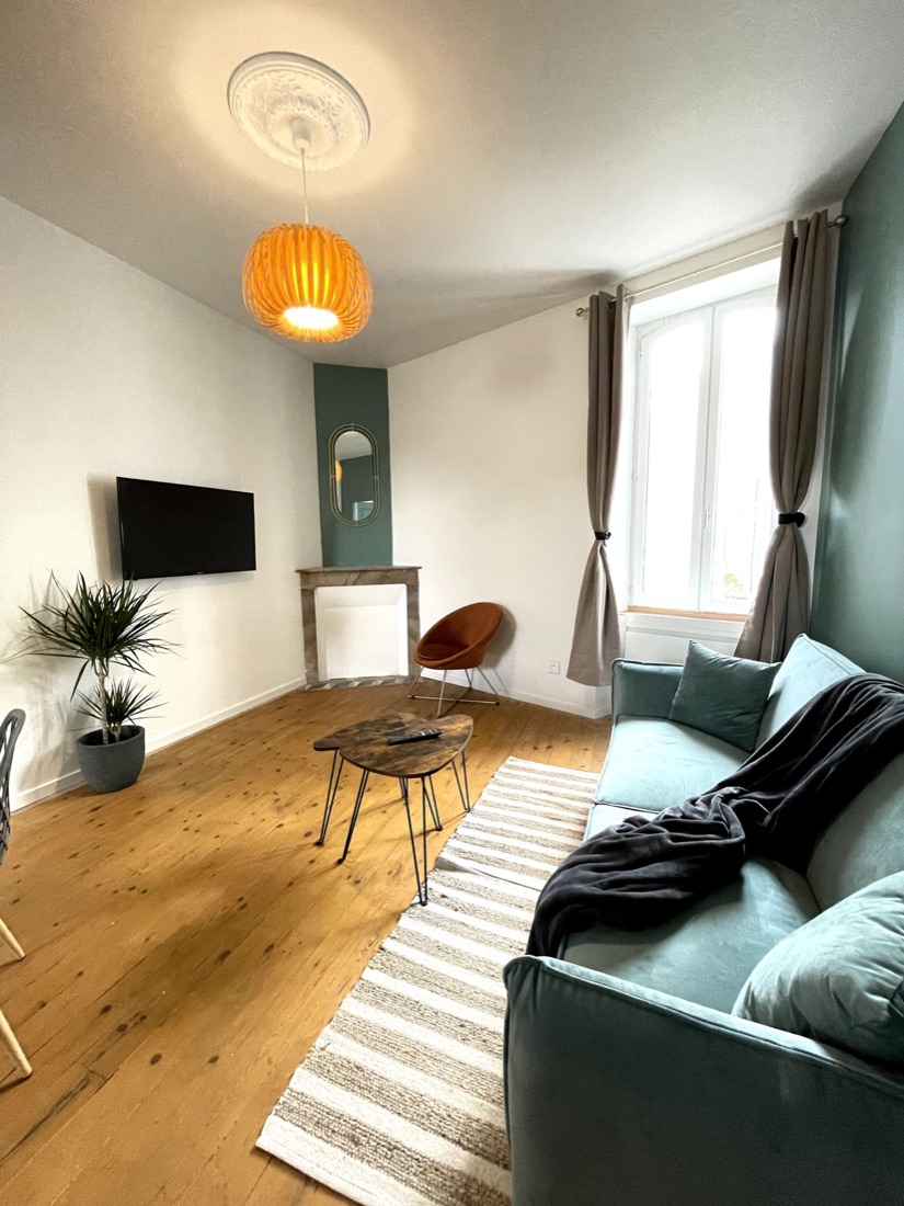 Salon avec canapé vert d’eau, cheminée en marbre et parquet ancien